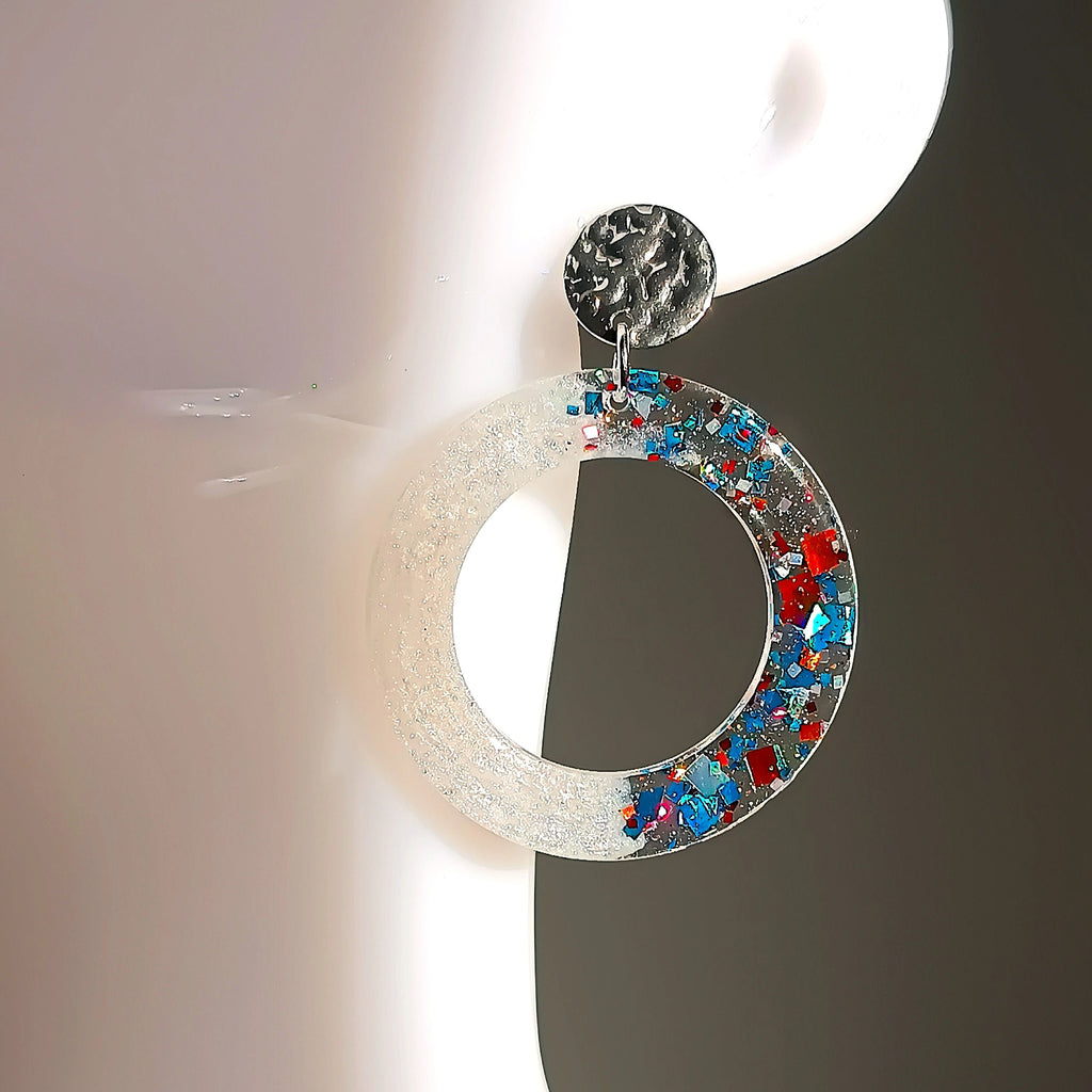 Boucle d’oreille en résine UV pailletée bleue, brun et argent, forme ronde, portée sur un mannequin